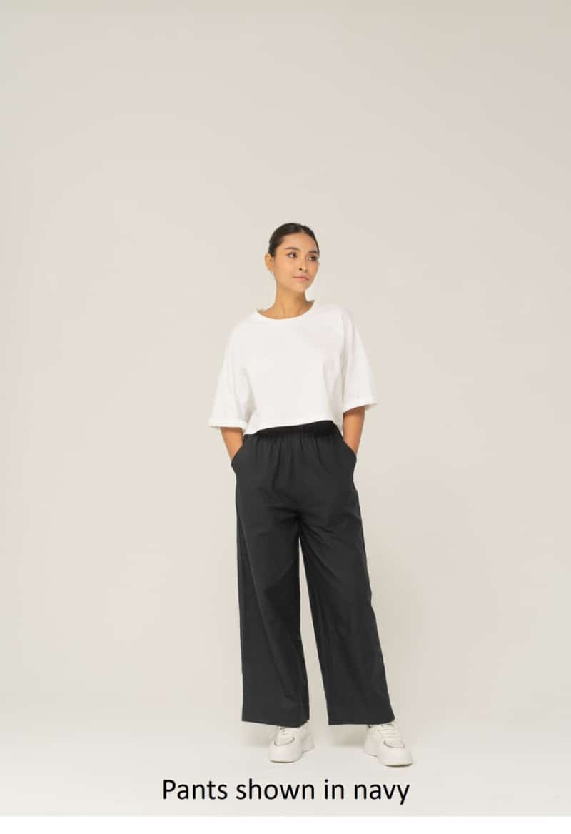 A person in upcycled white shirt and unisex navy wide leg pants by Dorsu brand