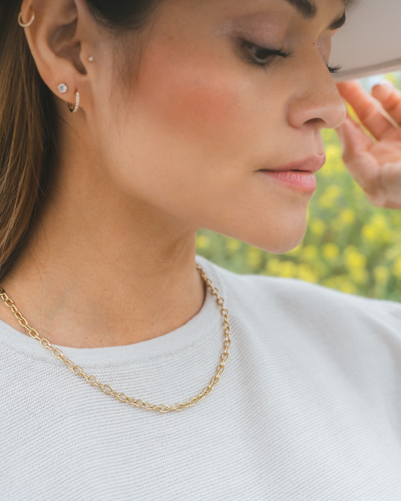 Washed Ashore brand recycled thick chain gold necklace, ama huggy earrings, and white sapphire element studs